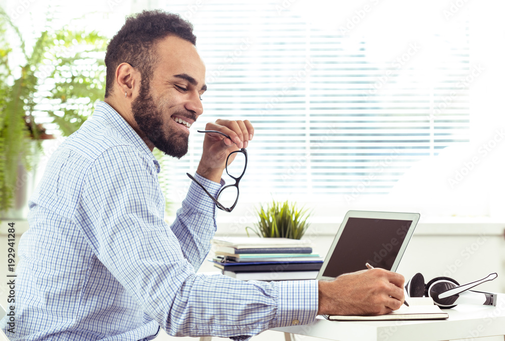 portrait of handsome African black young business man working on laptop at office portrait of handsome African black young business man working on laptop at office