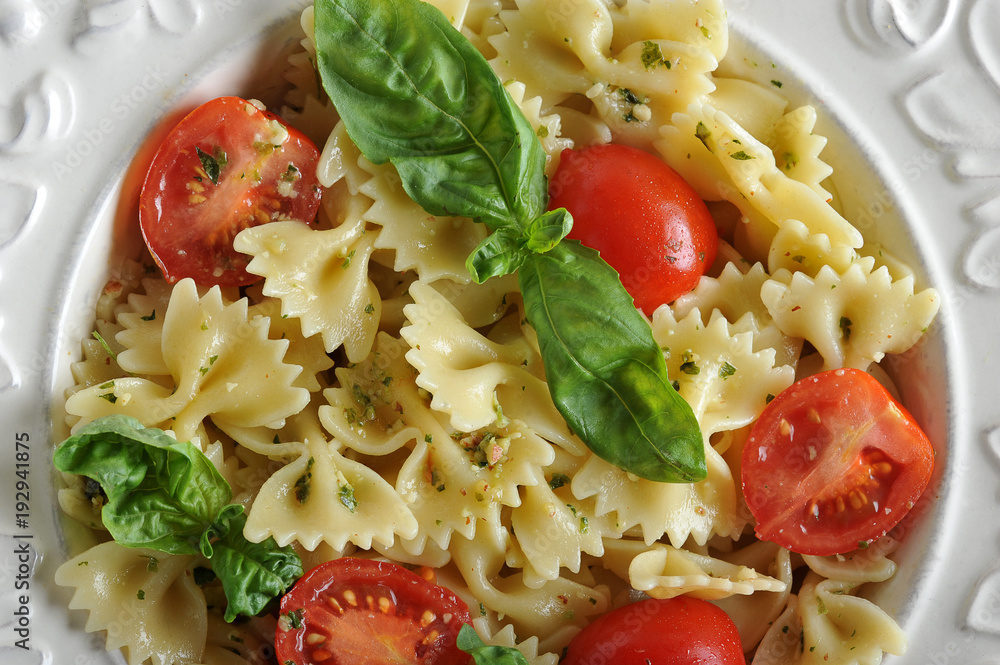 Pasta farfalle with pesto sauce and cherry tomatoes in a deep white ...