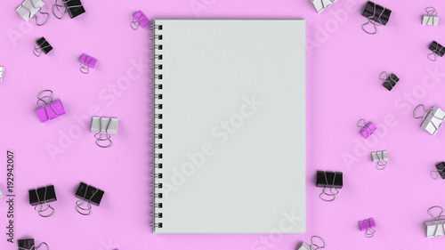 Blank spiral notebook with black, white and purple binder clips on purple table