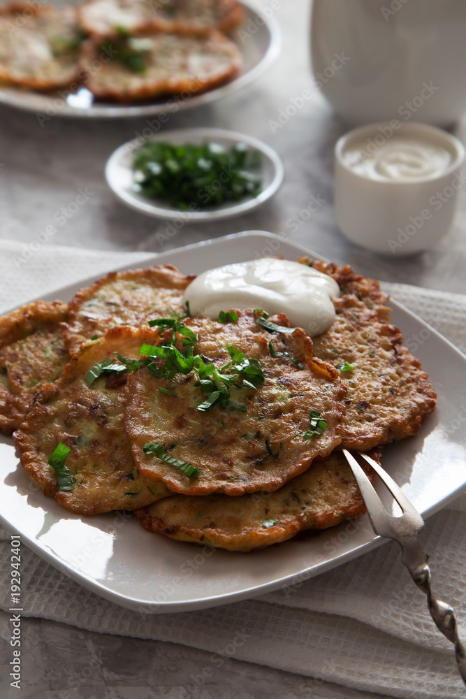 Vegetable pancakes with sour cream on white plate Vegetable pancakes with sour cream on white plate
