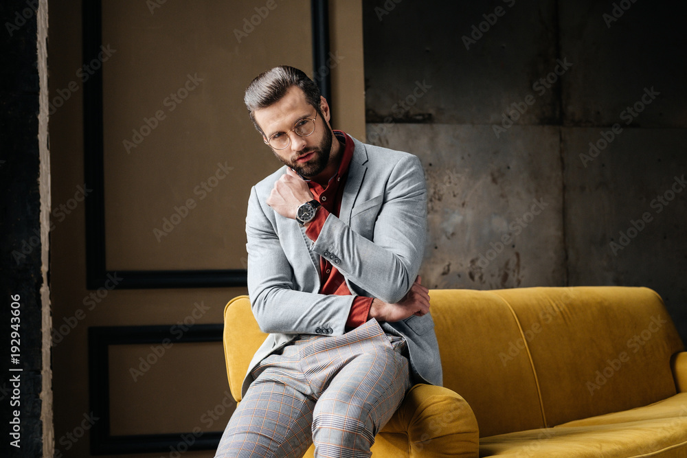 handsome elegant man in glasses and suit sitting on sofa handsome elegant man in glasses and suit sitting on sofa