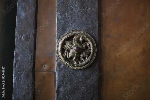 Bronze unicorn on a wooden door.