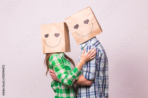 Love couple covering their faces with paper bag over white background photo