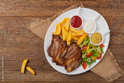 Grilled pork neck served with French fries and salad.