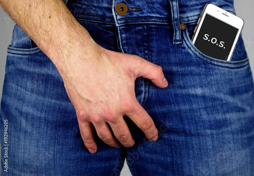 Young man with mobile phone in jeans pocket.Watch out for radiation.The cell phone radiation  harms male fertility.Be careful.