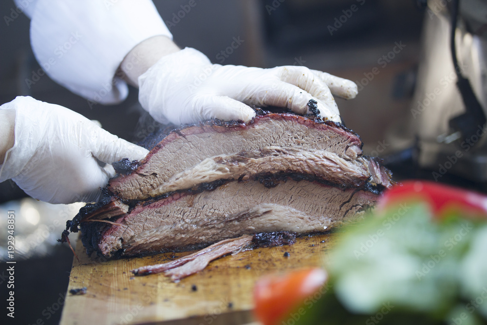 Large piece of smoked meat on a wooden board carved by butcher