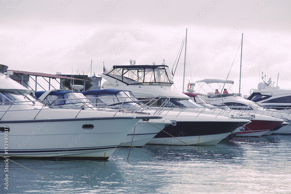Fototapeta premium Yachts on the pier in the port in cloudy weather 