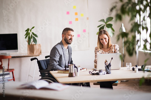 Two business people with wheelchair in the office. photo