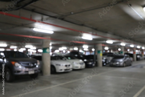 Abstract blurred image background of parking area, ground floor for car parking, Concrete skeleton interior design, Large private garage. shot in the evening with boken light from neon. © narin_nonthamand