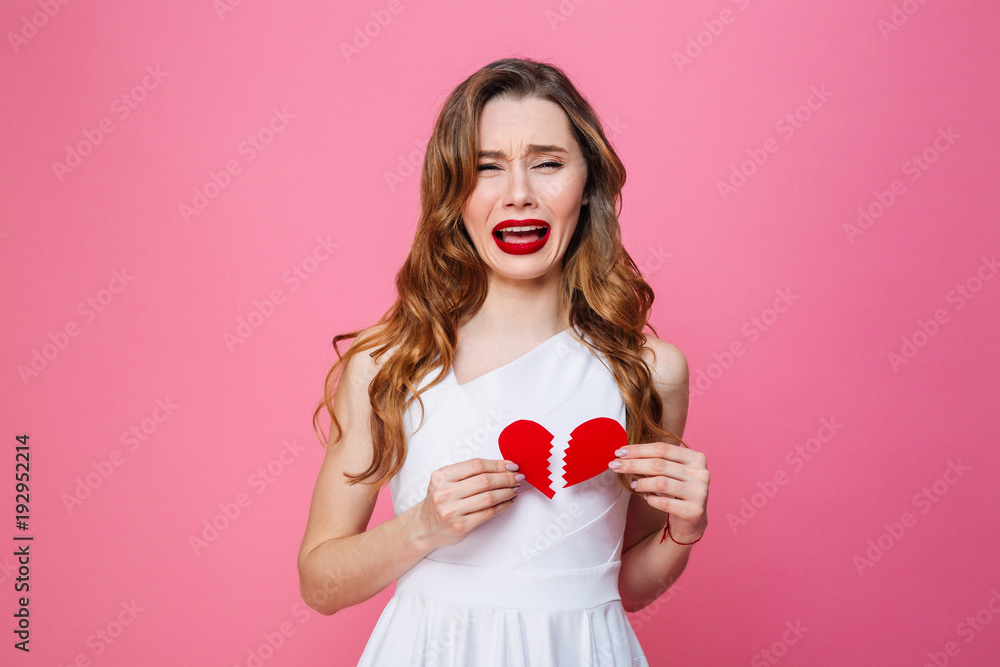 Sad woman standing isolated holding broken heart Sad woman standing isolated holding broken heart