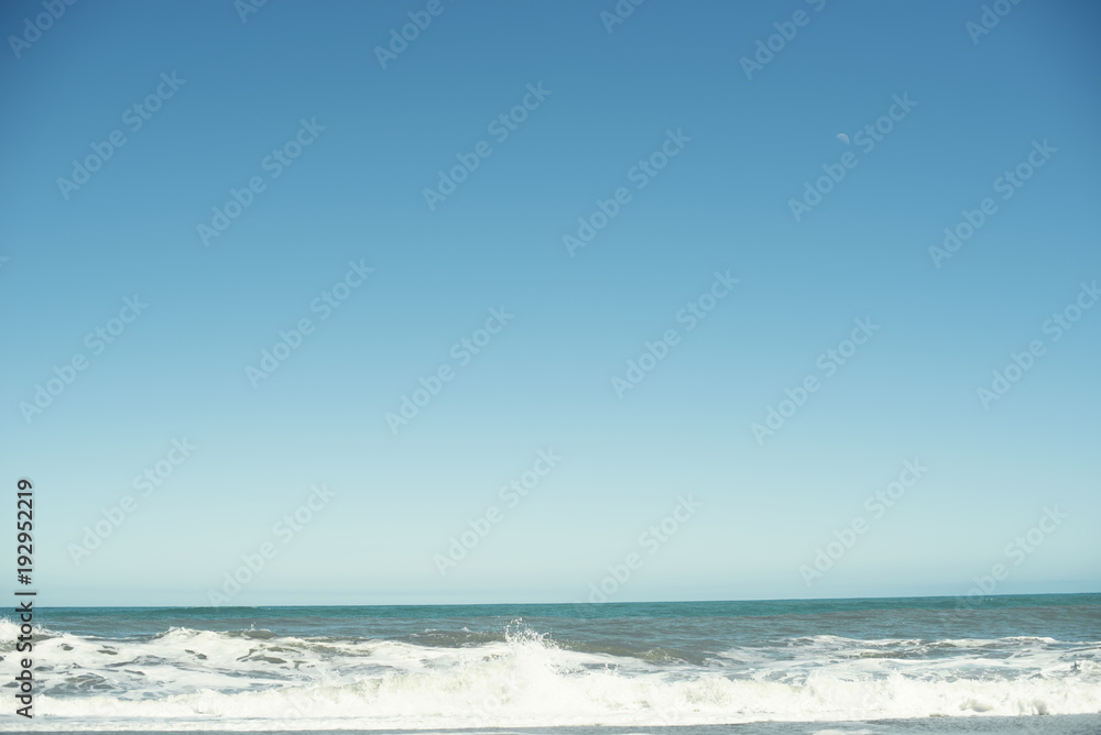 Paisaje de playa minimalista con un amplio cielo azul.