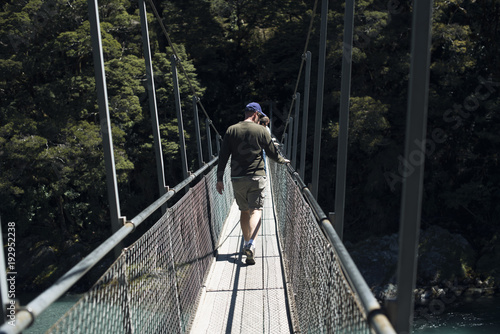 Hombre joven posando frente a un bosque en un puente de madera
