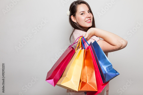 Adorable brunette shows many shopping bags from mall