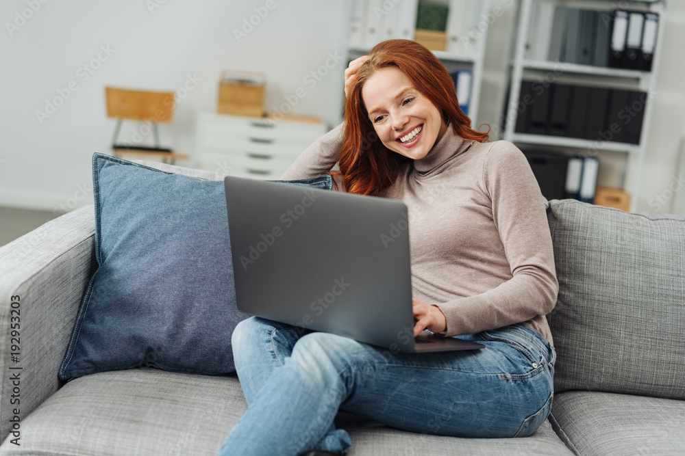 Young woman relaxing on a sofa with a laptop Young woman relaxing on a sofa with a laptop