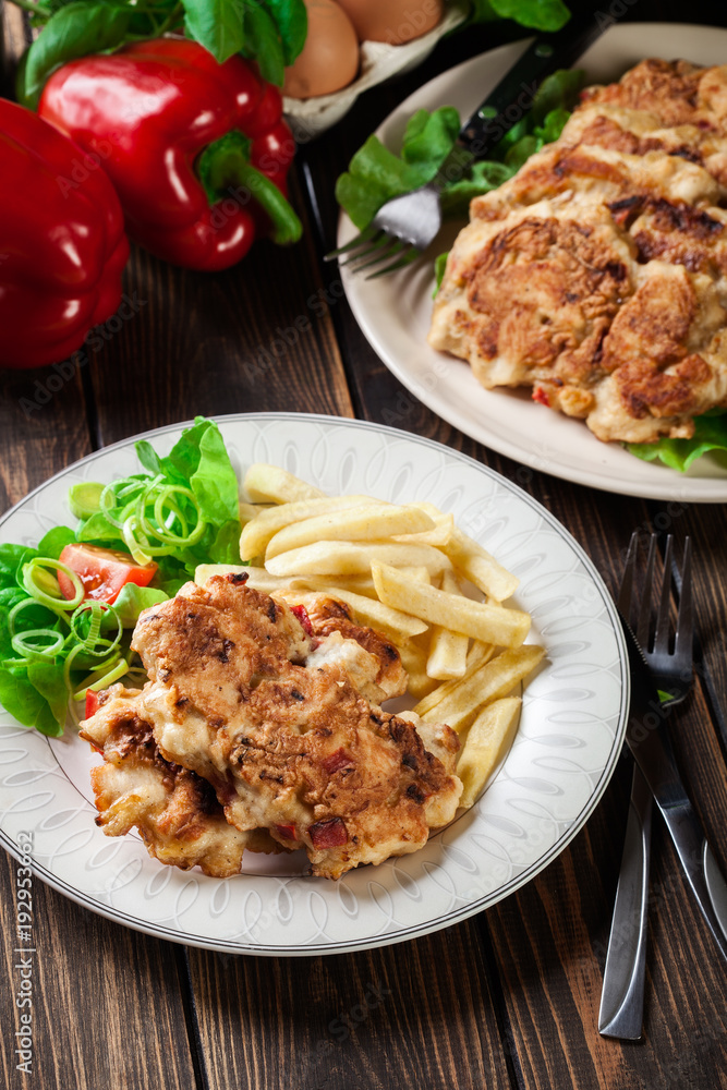 Chicken medallions with red peppers served with chips Chicken medallions with red peppers served with chips
