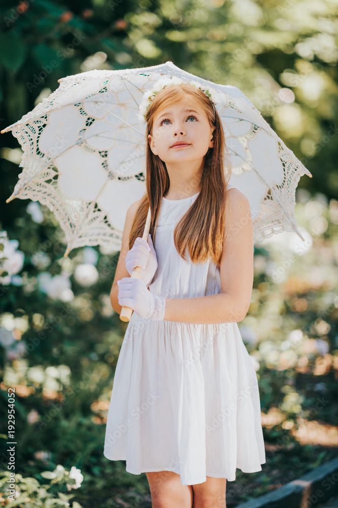 Outdoor portrait of romantic little girl wearing white dress