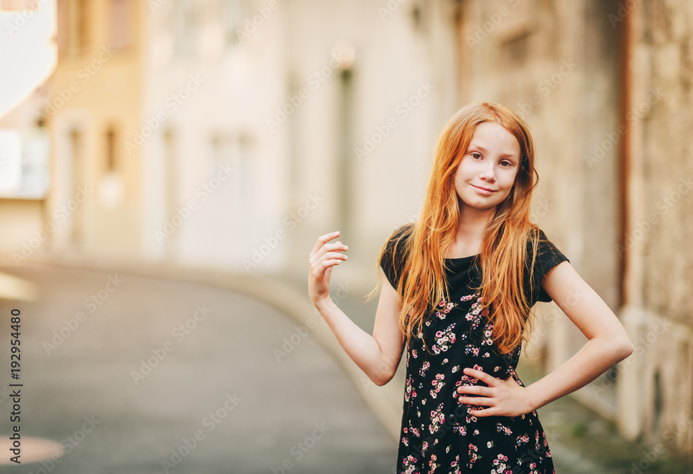 Outdoor fashion portrait of happy red-haired girl