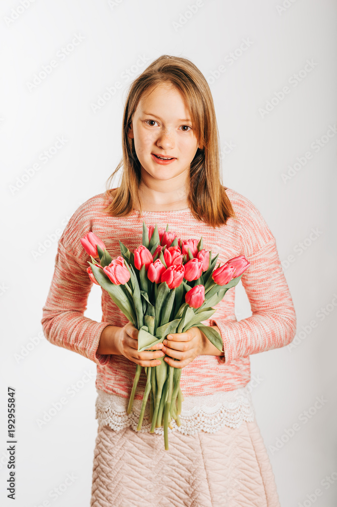 Studio image of cute preteen girl wearing sweatshirt, holding pink tulips Studio image of cute preteen girl wearing sweatshirt, holding pink tulips