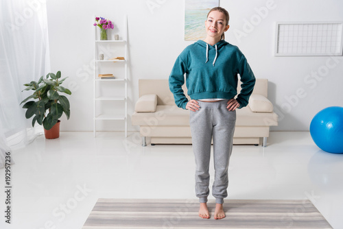 smiling girl exercising and looking at camera at home