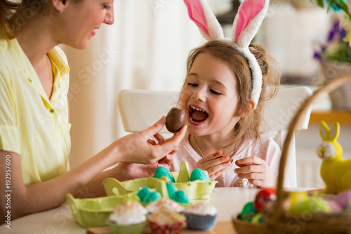 Canvas Print Mother and daughter celebrating Easter, eating chocolate eggs