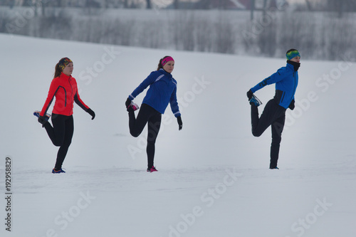 Group of athletes warming up and stretching before exercise in winter forest