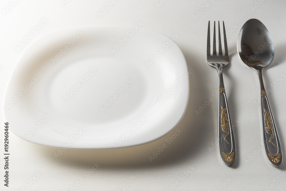 Fork, spoon and white plate on white background Fork, spoon and white plate on white background