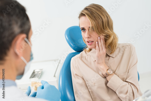 Female patient suffering from toothache in modern dental clinic