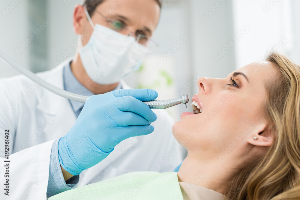 Female patient at dental procedure using dental drill in modern dental clinic Female patient at dental procedure using dental drill in modern dental clinic