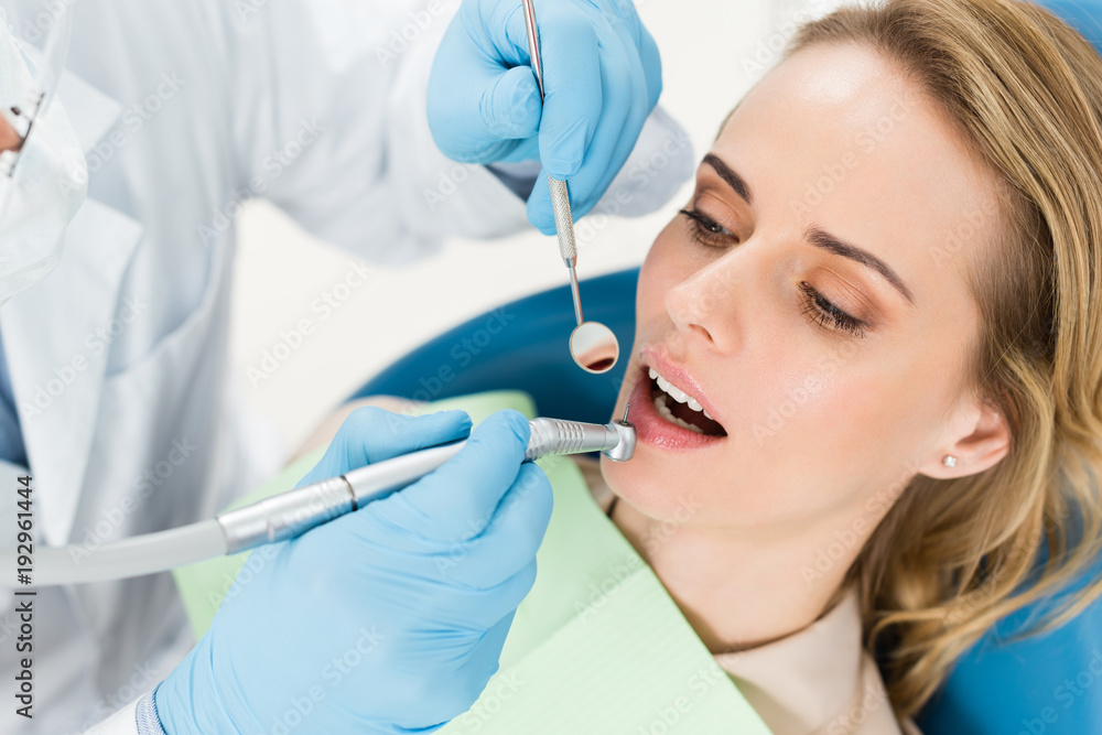 Doctor using dental drill during procedure in modern dental clinic Doctor using dental drill during procedure in modern dental clinic