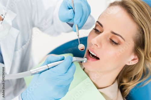 Doctor using dental drill during procedure in modern dental clinic