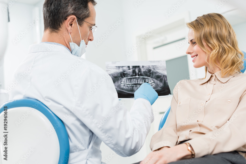 Woman consulting with dentist looking at x-ray in modern clinic Woman consulting with dentist looking at x-ray in modern clinic