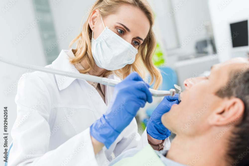 Doctor using dental drill during procedure in modern dental clinic Doctor using dental drill during procedure in modern dental clinic