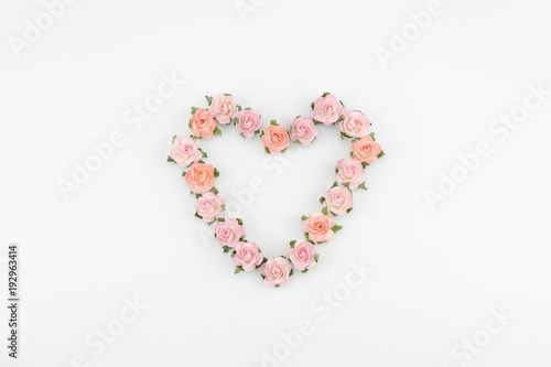 Heart shape wreath made from pink and orange paper flowers on white background with copy space