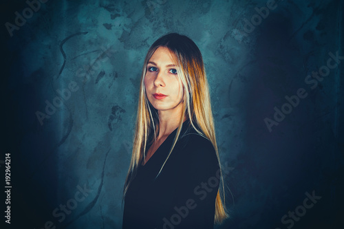 Attractive pretty young model posing against a dark studio background with copy space looking. Atomic blonde woman. Dramatic look