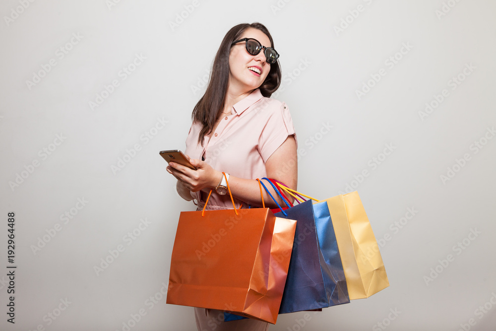 Very beautiful girl smiling and looking over shoulder with shopping bags in her hand Very beautiful girl smiling and looking over shoulder with shopping bags in her hand