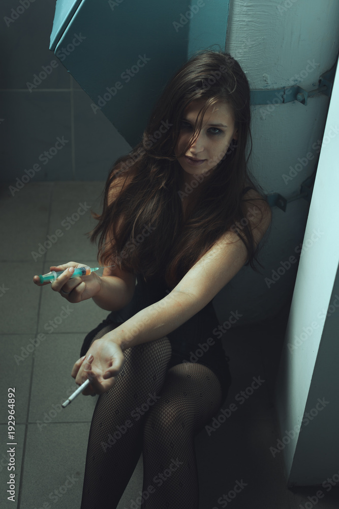 Woman is a drug addict with a syringe, she injects into the hand of the drug.