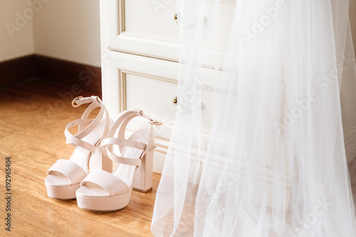 Bridal pink shoes standing in front of the nightstand. Bridal veil falling down from the nightstand.
