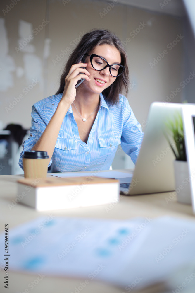 Beautiful young business woman sitting at office desk and talking on cell phone. Business woman Beautiful young business woman sitting at office desk and talking on cell phone. Business woman