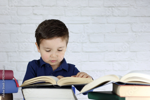 ni  o peque  o leyendo un libro y rodeado de muchos libros