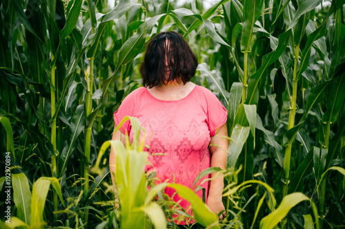 Strange unusual woman portrait in cucumber field. Female hiding her face. Girl outdoor at nature in summer with hair cover her face. Child of the corn. Scarecrow in field. Adult lonely person have fun photo
