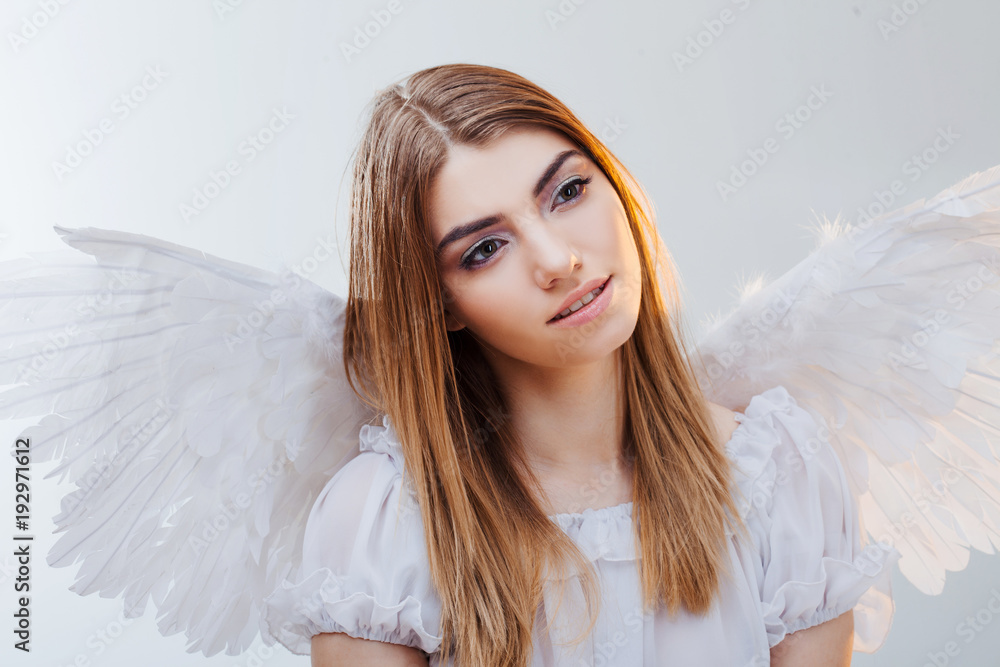 An angel from heaven. Young, wonderful blonde girl in the image of an angel with white wings. Portrait close-up An angel from heaven. Young, wonderful blonde girl in the image of an angel with white wings. Portrait close-up