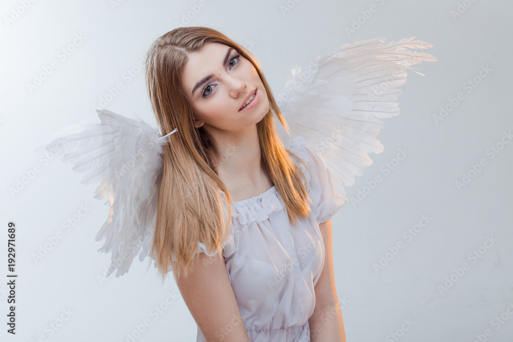 An angel from heaven. Young, wonderful blonde girl in the image of an angel with white wings. Portrait close-up An angel from heaven. Young, wonderful blonde girl in the image of an angel with white wings. Portrait close-up
