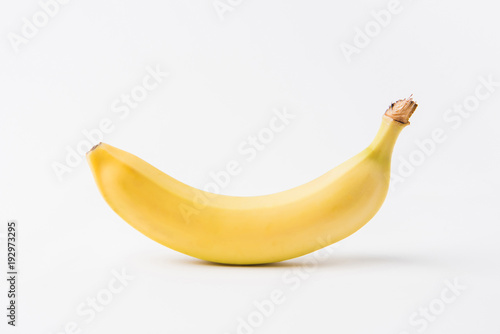 raw unpeeled banana laying on white background