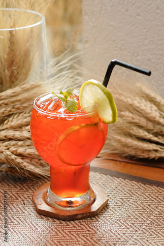 Iced lemon tea with lime and mint decoration on wooden and cereal background - Soft focus photo