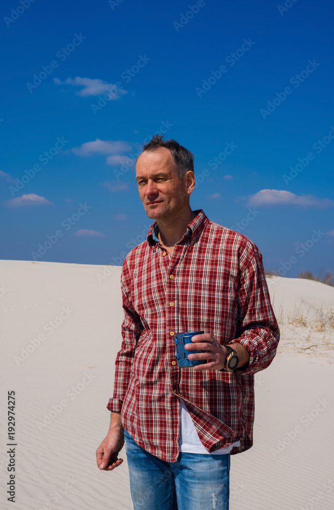 Happy traveler drinks coffee in desert