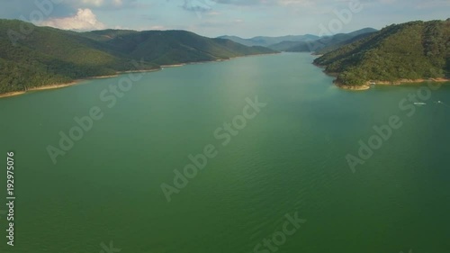 Backward flight over beautfiul lake among green hills at sunset photo