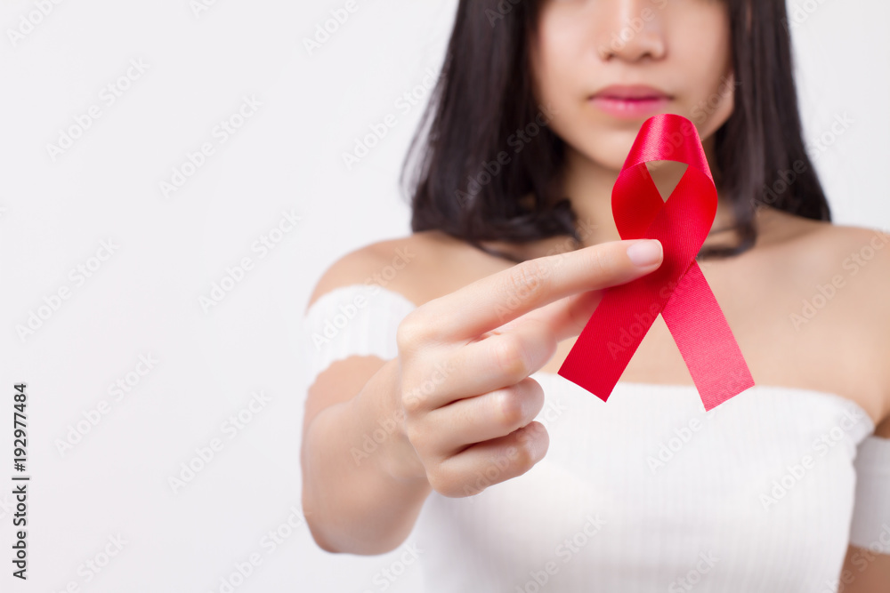 woman hand holding red ribbon bow, hiv or aids awareness symbol presented by woman in studio shot. medical, charity, fund raising concept for red ribbon hiv aids day awareness woman hand holding red ribbon bow, hiv or aids awareness symbol presented by woman in studio shot. medical, charity, fund raising concept for red ribbon hiv aids day awareness