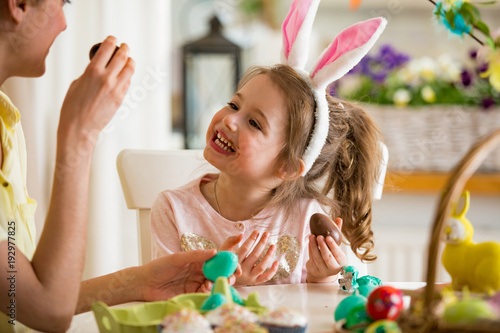 Photography Mother and daughter celebrating Easter, eating chocolate eggs