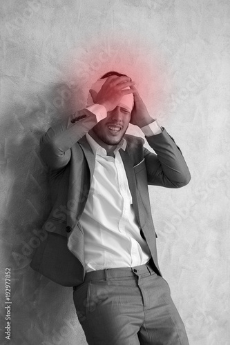 Overworked young man having headache once onerous operating day.sick man headache, dizzyness, sinus inflammation, stress, migraine.black and white body pain concept