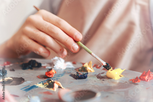No limits for creativity. Talented child painting something and mixing oil paints on a palette while taking part in a painting session.